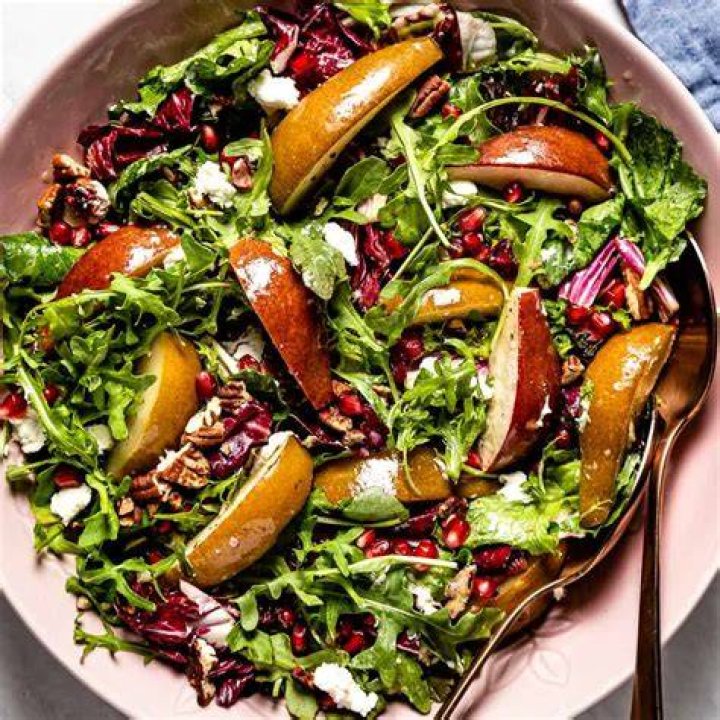 Roasted Pear Salad roasted pear salad with mixed greens, candied pepitas, and blue cheese in a wooden bowl